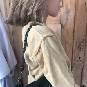  - En brun gul tröja med rufflade detaljer runt axeln. Bra kvalite och blir inte nopprig. Sitter fint på! 