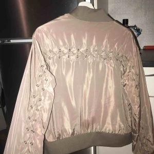  - Snygg bomber jacka från NA-KD, flätor bak och vid armarna 