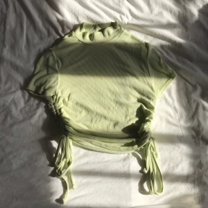 Topp med fin detajl - En söt t-shirt med fina knyt-detaljer på sidorna som går att spänna ut och in hur man vill🌟 Köparen står för frakten💕  