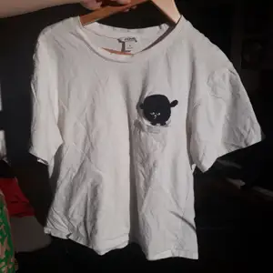 Vit t-shirt med en liten lurvig filur på som flyger ut ur en ficka. Från Monki. Lite croppad. Väl andvänd