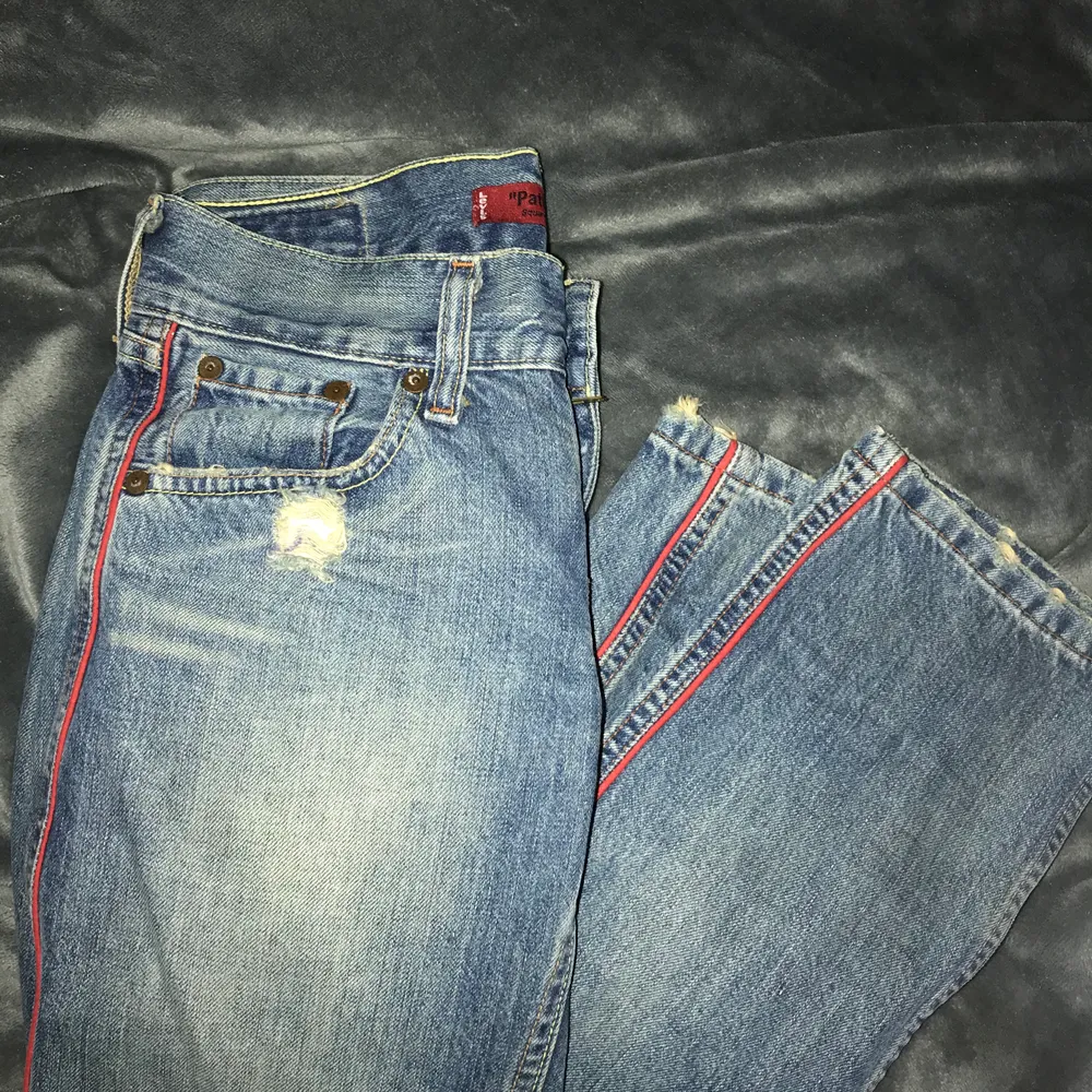 Lågmidjade jeans köpta secondhand så vet ej om det är äkta levis. Fickorna bak sitter även långt ner. Röda ränder på sidorna av benet. Lägger sig fint över skorna på mig som är 165cm lång. Hittar ingen storlek men den uppskattas till 24” i midjan :). Jeans & Byxor.