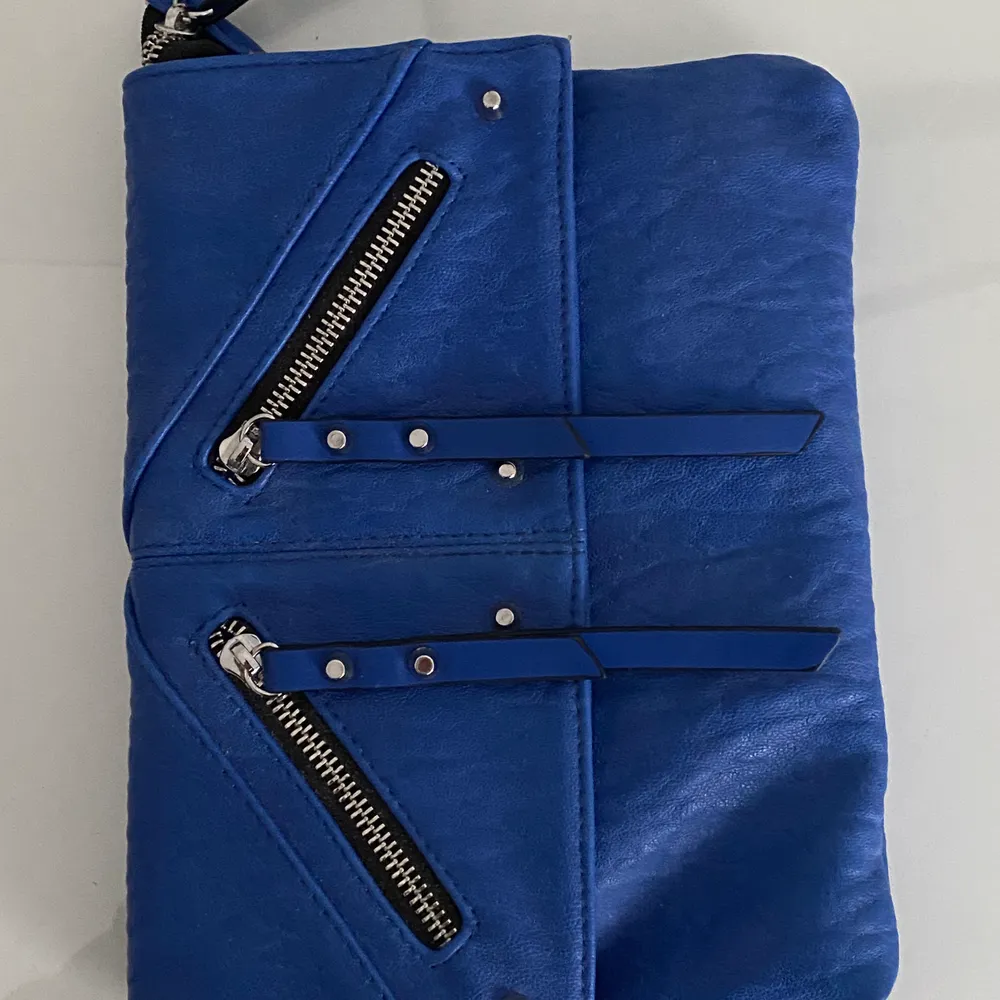 En blå väska med detaljer. Väskor.