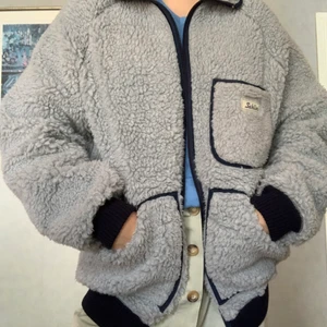 Teddyjacka/fiberpäls. Inkl. frakt! - Superfin ljusgrå teddyjacka i workerstil med mörkblå detaljer. Varm, mjuk och mysig! Storleken är L, men passar även mindre. Älskar denna, men använder den för sällan :( Frakt ingår!