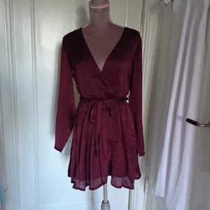  - Vinröd omlott satin klänning från nelly. Frakt 26kr betalning via swish 