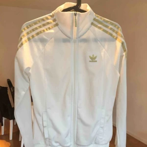  - Superfin och lite ovanlig Adidas tröja Vit med detaljer i guld och är i mycket bra skick Kom med bud och kolla gärna mina andra annonser, kan samfrakta i den mån det går Går ej att swisha, men går bra med kontanter eller banköverföring