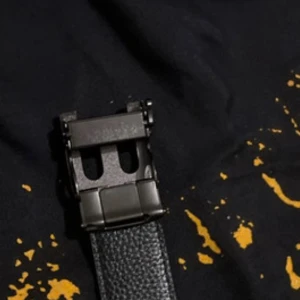 Burberry bälte  med GG-mönster och metallspänne - Säljer ett stilrent burberry bälte i svart och grått med klassiskt GG-mönster längs hela bandet. Bältet har ett robust metallspänne med unik design och detaljer i silver. Perfekt accessoar för att lyfta din outfit med en lyxig touch.