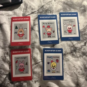 SKZSHOP HIPTAPE (HOP) Holiday Cards - Samling med fem färgglada kort med söta, handritade djurfigurer i julkläder, skapade av medlemmarna i Stray Kids. Perfekt för fans av K-pop och Stray Kids som vill ha unika samlarkort med festligt tema. Varje kort har en personlig touch och signatur. (KOMMER MED FREEBIES) (30 STYCK! SKRIV VILKEN NI VILL KÖPA!) 