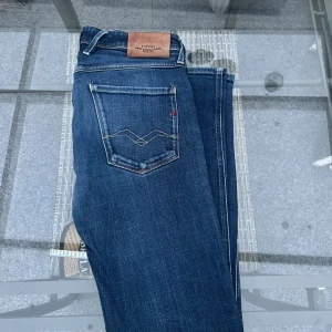 Replay Anbass jeans – W33 L32 - Snygga jeans från Replay, modell Anbass. Klassisk mörkblå tvätt med skön stretch som gör dem bekväma att bära. Modellnummer: M914Y.000.141 00 Tillverkade i Tunisien.  ✅ Storlek: W33 L32 ✅ Passform: Slim fit / rak modell ✅ Färg: Mörkblå ✅ Märke: Replay ✅ I fint begagnat skick – inga hål eller fläckar. Nypris ca 2000kr 