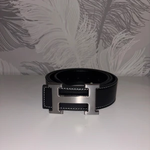 Svart H bälte - Fin svart H bälte som är helt ny. Den är 110cm lång. Och med bältet så får du ett litet metall verktyg som kan göra extra hål på bältet med hjälp av hammare. Tveka inte att dm:a vid frågor eller intresse!!