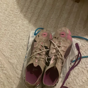 Puma fotbollsskor med zebra-mönster ultra 5 ultimate  - Säljer ett par grymma Puma fotbollsskor i storlek 43 med coolt zebra-mönster på sulan och detaljer i rosa, svart och beige. Skorna har snörning och en lätt, syntetisk ovandel som ger bra känsla på planen. Perfekt för dig som vill sticka ut med din stil på matchen.