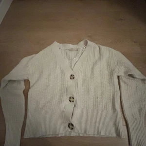 Beige stickad kofta med knappar - Mysig beige stickad kofta med stora dekorativa knappar framtill. Inga defekter!