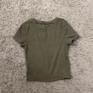 Olivgrön ribbad topp från FSBN Sister - Säljer en olivgrön ribbad topp från FSBN Sister i storlek XXS. Toppen har rund halsringning och korta ärmar, tillverkad i mjuk bomull. Enkel och stilren design som är lätt att matcha med dina favoritjeans eller kjol.