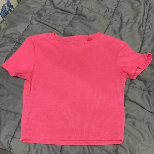 Rosa ribbad topp från new yorker XS - Säljer en rosa croppad topp från new yorker i storlek XS. Toppen har korta ärmar, rund hals och är ribbad i materialet 