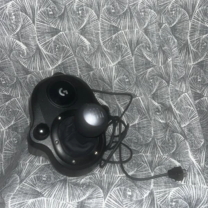 Logitech G Driving Force Shifter - Logitech G Driving Force Shifter för racing-spel. Kompatibel med G29 och G920 rattar. 6-växlad manuell växelspak, robust konstruktion och monteringsklämma. Kabel och kontakt i gott skick, inga fel eller större slitage.