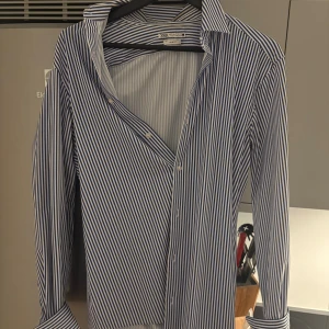 Blårandig skjorta från Zara Slim Fit - Snygg skjorta från Zara i slim fit-modell med blå och vita ränder. Klassisk krage, långa ärmar och knappar framtill. Perfekt för dig som gillar stilrena och fräscha plagg med modern passform.