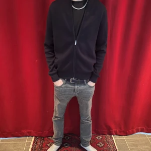 Svart zip-kofta från H&M - Svart kofta med dragkedja från H&M, perfekt för chill dagar. Långärmad med ribbade muddar och enkel design. Skön passform och funkar till jeans eller joggers. Snygg att ha öppen eller stängd beroende på stil.