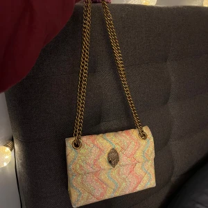 Glittrig unik  Kurt Geiger väska - Färgglad axelväska från Kurt Geiger med glittrigt vågmönster i rosa, gult, blått och beige. Väskan har kedjerem i guld, quiltad framsida och ikoniskt lås. Sparsamt använd så i nyskick. Köpt för  närmre 3000 💕 är i den mindre modellen på väska 