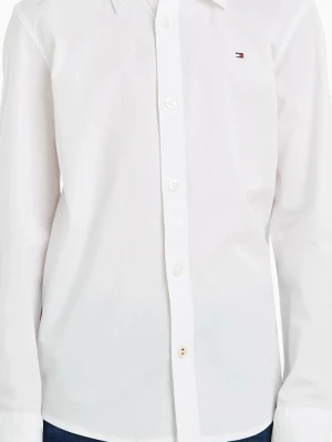 Vit skjorta från Tommy Hilfiger stl 164 - Klassisk vit skjorta från Tommy Hilfiger med lång ärm och knappar framtill. Skjortan har en liten broderad logga på bröstet och är tillverkad i bomull. Perfekt för en clean och stilren look. Lite struktur på det vita så inte helt slät