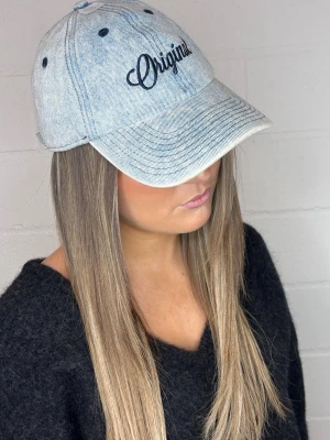 Ljusblå denimkeps med brodyr - Snygg ljusblå keps i denim med svart broderad text 'Original' framtill. Klassisk sexpaneldesign med böjd skärm och justerbar rem bak. Perfekt accessoar för en avslappnad streetstyle-look.