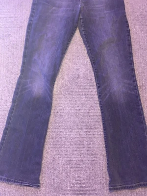 Mörkblå bootcut jeans med kontrastsöm - Snygga mörkblå bootcut jeans med klassisk femficksmodell och orange kontrastsöm på bakfickan. Jeansen har en lätt tvättad look och raka ben som går ut lite nedtill. W29 L32. Pris kan diskuteras