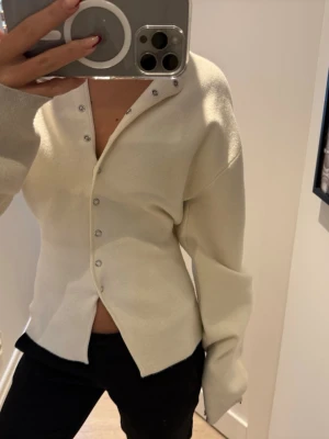 Vit tröja med knappar från Gina Tricot - Snygg stickad tröja från Gina tricot med knappar som är figur sydd. Perfekt till alla tillfällen.