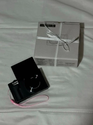 Panasonic Ny Lumix TZ99 digitalkamera svart Canon g7x dupe - Snygg svart digitalkamera från Panasonic, modell Lumix TZ99 med Leica-objektiv och vinklingsbar skärm. Perfekt för resor och vloggning. Levereras med originalkartong och handledsrem, skyddsfodral och har usbc laddning. Kameran är nästan till identisk till Canon g7x med bättre zoom och touch skärm. Säljer då den inte används.                                Först till kvarn!