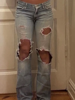 Ljusblåa jeans med slitningar  - Midjemåttet rakt över är 37cm o innerbenslängden 78cm