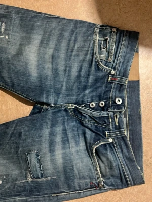 Blå jeans från dondup - Säljer ett par blå jeans från dondups. Med slitningar  och lagade detaljer på benen. Jeansen har en klassisk femficksmodell och tydliga slitningar för en cool, avslappnad look.