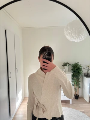 Beige omlottkofta med knytband - Snygg beige omlottkofta med knytband i midjan. Säljer denna då den aldrig kommer till användning längre. 🤍