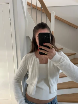 Vit långärmad bolero  - Supermjuk och fluffig vit bolero kofta från Rino & Pelle. Står storlek L på plagget men passar även bra för XS-M beroende på hur man vill att den ska sitta. 