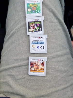 Nintendo 3DS spelpaket (4 spel) - Fyra Nintendo 3DS-spel: Rabbids 3D, Luigi's Mansion 2, Ghost Recon Shadow Wars och Nintendogs + Cats. Alla spel är på små, vita plastkassetter med färgglada etiketter. Perfekt för dig som gillar äventyr, strategi och djurspel på 3DS.