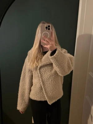 Teddyjacka - Säljer en supermjuk och fluffig beige teddyjacka med hög krage och omlottstängning. Storlek xxs men passar även xs.