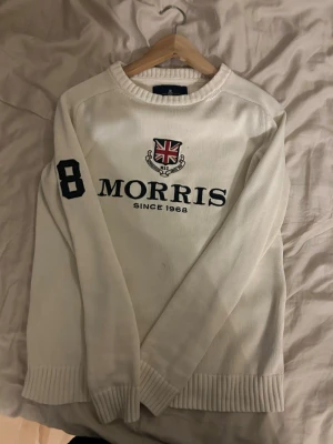 Vit stickad tröja från Morris - Vit stickad tröja från Morris med rund halsringning och ribbade muddar. Stor svart '68' på ena ärmen och Morris-logga med brittisk flagga och texten 'Since 1968' på bröstet. Klassisk och stilren design, perfekt för dig som gillar 𝐆𝐫𝐢𝐬𝐜𝐡 stil. Pris går att diskuteras.