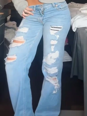 Ljusblåa baggy ripped jeans - Säljer ett par ljusblåa baggy jeans med stora slitningar och hål framtill. Jeansen är low waist, vida ben.  Materialet är denim i bomull.