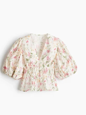 Blommig blus med puffärm - Supersöt blommig blus med v-ringning och puffiga korta ärmar. Blusen har smock i midjan och ett romantiskt blommönster i rosa och grönt på vit botten. 