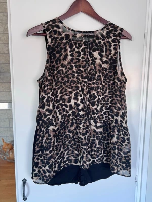 Leopardmönstrad ärmlös topp med dragkedja i ryggen från Kappahl, storlek 40/42  - Försvinner den 31:a mars om den inte blivit sålt innan dess. Snygg ärmlös topp med leopardmönster i svart och beige/brun. Toppen har dragkedja i ryggen och är i mycket bra skick! Luftig och skön mot huden.