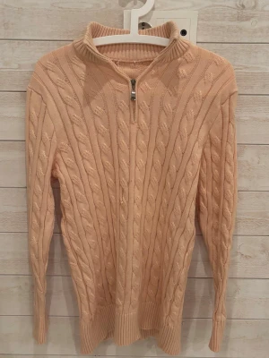 Beige kabelstickad tröja med halvzip - Kabelstickad tröja i beige med halv dragkedja framtill och hög krage ||| Tröjan har långa ärmar och ribbade muddar vid ärmslut och nederkant ||| Perfekt för lager på lager och ger en klassisk/ Old money look||| hör av dig vid minsta lilla fundering /// GC