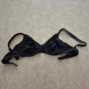 Behå - Snygg svart behå från Triumph i storlek 75B. Klassisk trekantsform med justerbara axelband och enkel knäppning i ryggen. Tillverkad i mjukt och följsamt material som sitter skönt och ger bra stöd.