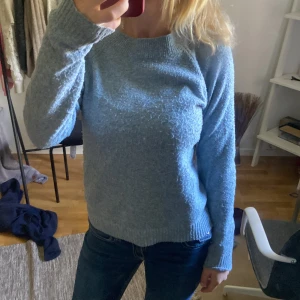 Ljusblå stickad tröja med rund hals - Mysig ljusblå stickad tröja med rund halsringning och långa ärmar. Tröjan har en enkel och klassisk design med ribbade muddar vid ärmslut och nederkant. Perfekt för lager-på-lager och chill dagar.