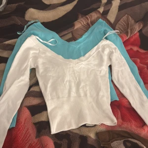 V-ringad ribbad topp från PMK basic - Två långärmade toppar i vitt och ljusblått från PMK basic. Båda har djup v-ringning, ribbad midja och smala knytband vid axlarna. Modellen är croppad med lätt vågig nederkant och sitter snyggt figurnära. Perfekt för dig som gillar stilrena och trendiga basplagg. Aldrig använt de som man ser säljer 1 för 40kr 2 för 70kr