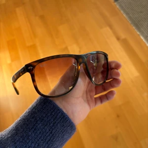Bruna Ray-Ban solglasögon pilotmodell - Snygga solglasögon från Ray-Ban i klassisk pilotmodell med brunmelerad båge och bruna tonade glas. Bågarna har en cool, lite retro känsla och passar perfekt för dig som vill sticka ut med stil. Ray-Ban-logga på linsen och metall-detaljer vid gångjärnen. Lite skrapmärken på glaset