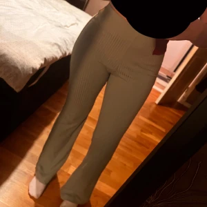 Ljusgröna ribbade bootcut byxor - Snygga ljusgröna ribbade byxor med bootcut-modell och mid midja. Byxorna har stretchigt material och sitter tajt upptill med utsvängda ben. Perfekta för en trendig och bekväm look.