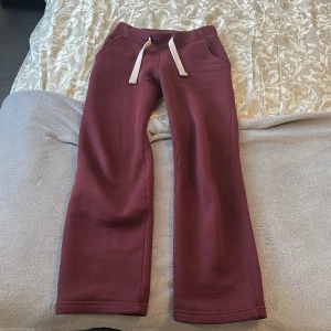 Vinrött sätt byxor&tröja  - Mysig vinröd hoodie från russemerch med dragkedja, luva och vita snören. Tröjan har långa ärmar, ribbade muddar och två stora fickor framtill. Perfekt för chill dagar och passar snyggt till matchande mjukisbyxor. Kostar 1200 nytt men använt lite så sänker i pris 