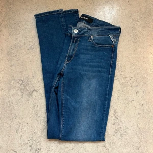 Blå Replay Jeans - Snygga blå jeans från Replay i klassisk femficksmodell i storlek W29 L32. Jeansen har slim passform och normal midja, med lätt slitning på låren för en cool look. Tillverkade i stretchigt denim för extra komfort. Perfekta för dig som gillar en smal siluett.