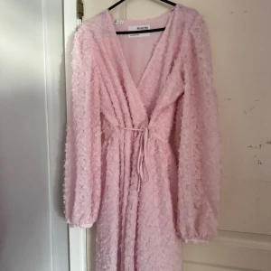 Ljusrosa omlottklänning Selected Femme - Säljer denna fina klänningen då jag bara använt den 1 gång till ett dop. Så fin ljusrosa med omlottmodell och knyt i midjan. Långa puffärmar och täckt av små 3D-blommor över hela. Perfekt till vår/sommar och till finare tillfällen🩷Från Selected Femme i storlek 36
