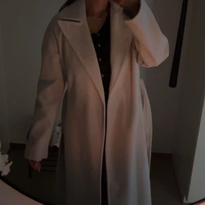 Beige kappa  - Pris förslag accepteras. en snygg beige kappa med bälte i midjan. Lång modell med klassisk look och fickor på sidorna. Perfekt för dig som vill ha en stilren och tidlös jacka till höst och vinter