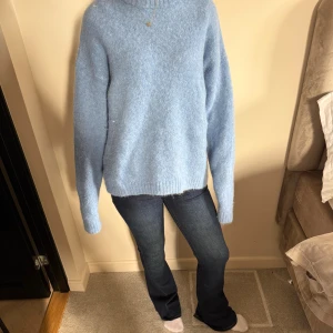 Ljusblå stickad tröja - Mysig ljusblå stickad tröja med lång ärm och avslappnad passform. Tröjan har en enkel design utan mönster och är perfekt för kyligare dagar. Den är mjuk och fluffig, vilket gör den extra skön att bära.