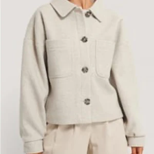 Beige overshirt med stora fickor - Snygg beige overshirt med stora bröstfickor och markerad krage. Jackan har stora knappar framtill och är långärmad med en rak, lite boxig passform. Perfekt för lager-på-lager och enkel att styla till olika outfits.