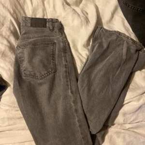 Grå jeansbyxor från Gina Tricot - Snygga grå jeansbyxor från Perfect Jeans med klassisk femficksdesign och dragkedja. Byxorna har en rak passform och normal midja, perfekta för en avslappnad men stilren look. Tillverkade i mjukt jeanstyg som är bekvämt hela dagen.