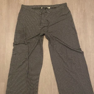 Randiga svarta mjukisbyxor med snörning - (Liten fläck som knappt syns) Säljer ett par svarta mjukisbyxor med tunna vita ränder och dragsko i midjan. Byxorna har raka ben och är gjorda i ett mjukt och bekvämt material, perfekta för chill dagar. Passar dig som gillar avslappnad stil.